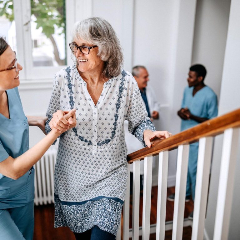 Nurse helping senior woman on stairs in nursing home