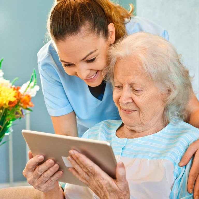 Nurse looking at senior woman using digital tablet