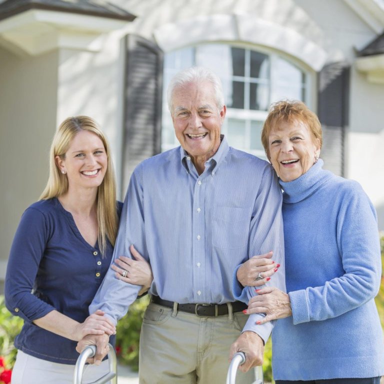 Woman with elderly parents standing in front of house