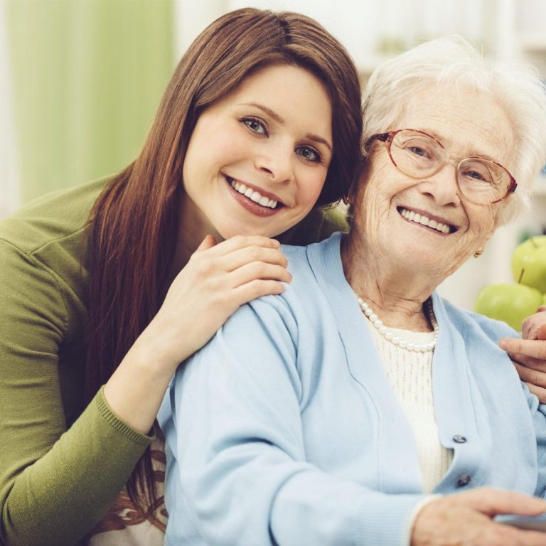 Young nurse embracing a happy senior woman