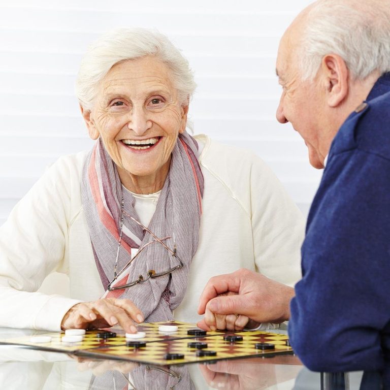 Happy senior couple playing checkers in a retirement home