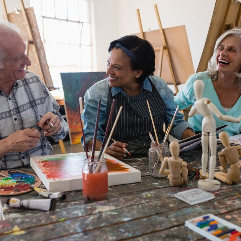 Cheerful senior male and female artists at table in art class