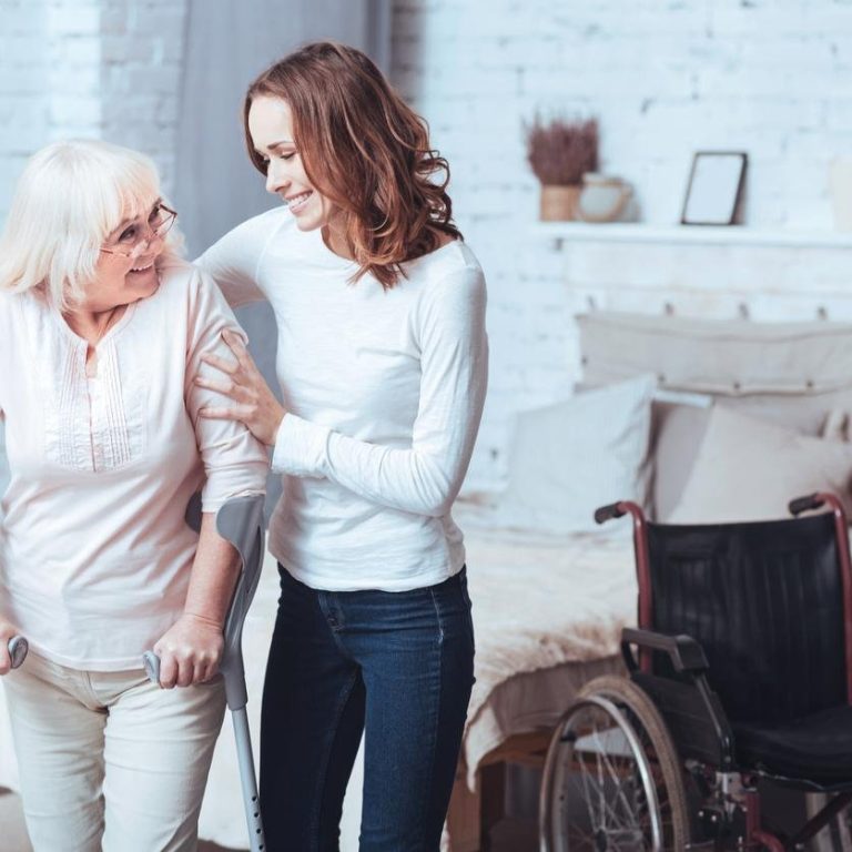 Lively young woman helping disabled aged lady at home